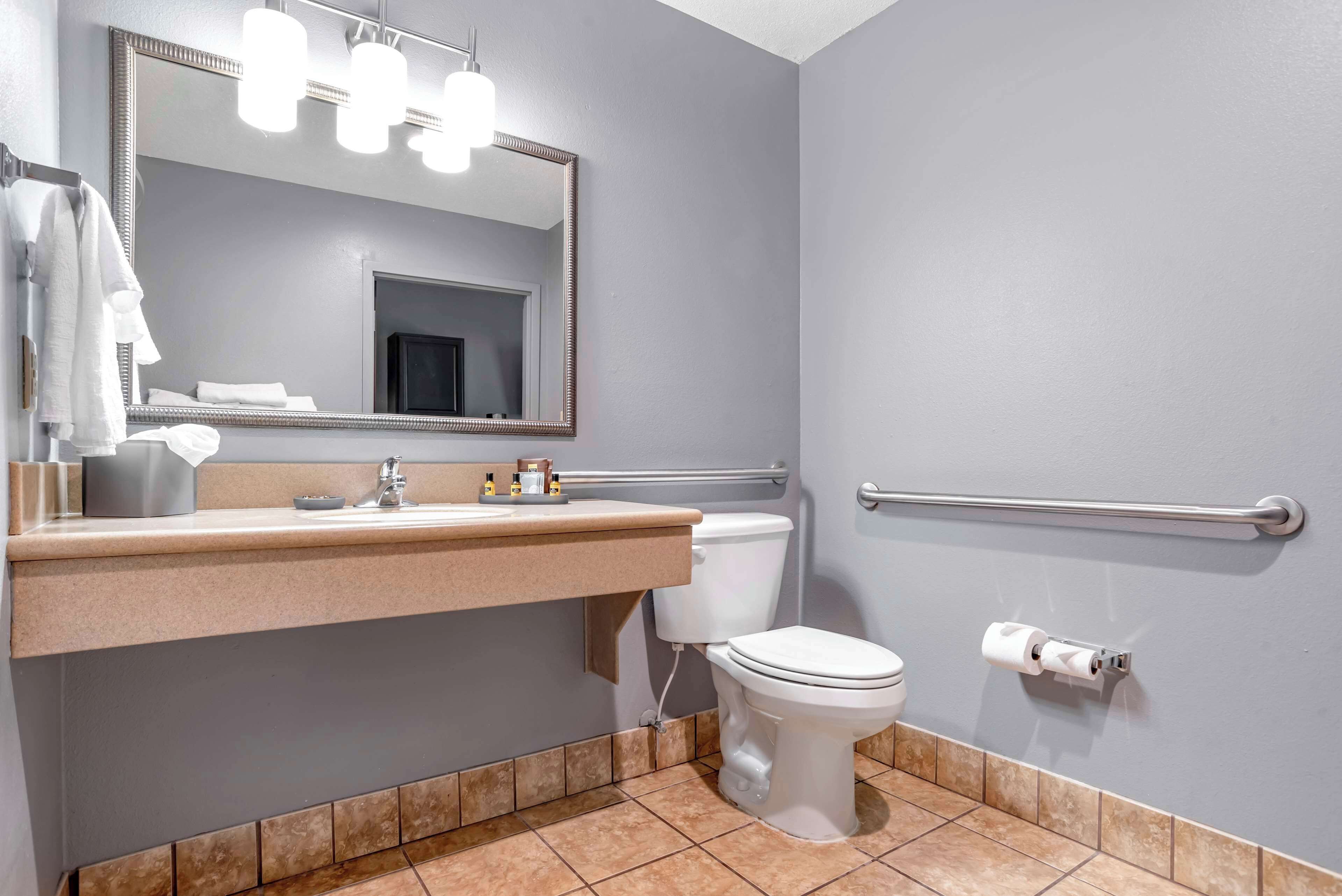 Un baño con inodoro, lavabo con espejo y un perchero para toallas.