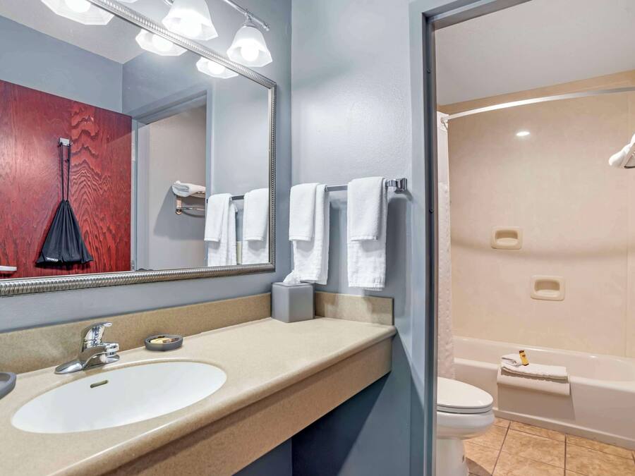 A bathroom with a sink, mirror, and shower.