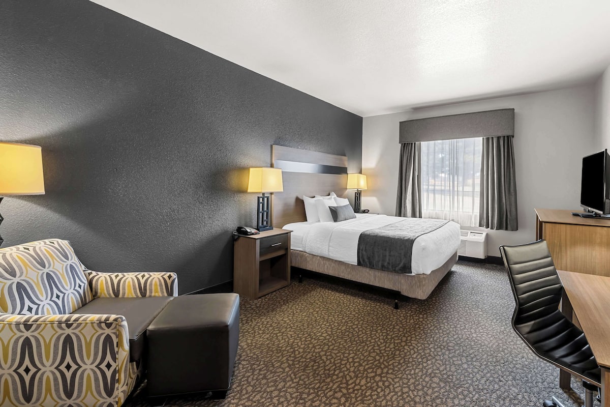 Une chambre d’hôtel comprenant un lit, des tables de chevet, un bureau, une chaise et un téléviseur.