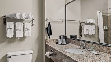 A bathroom with a toilet, sink, and towel rack with multiple towels.