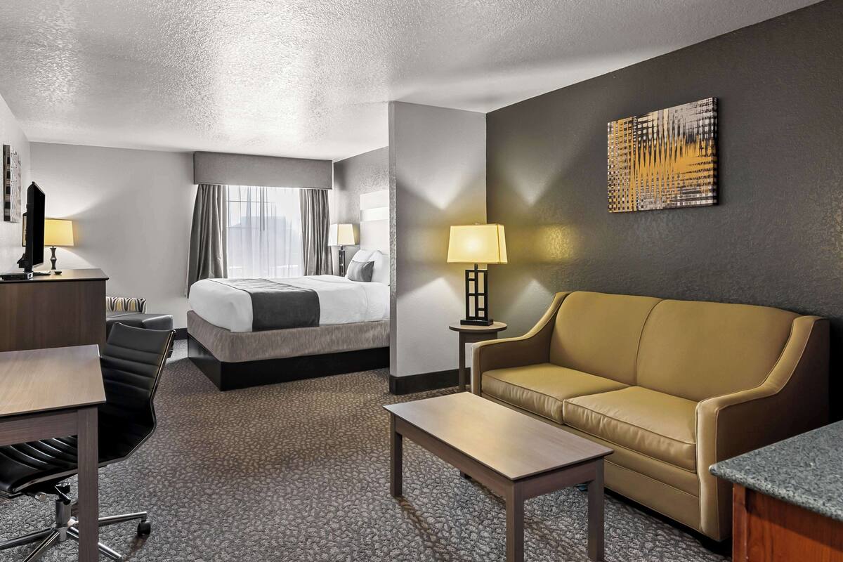 Une chambre d’hôtel avec un lit, un canapé, un bureau et une lampe.