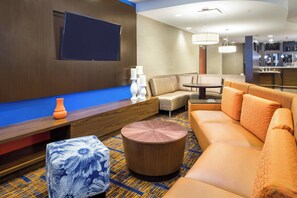 Un hall d’hôtel moderne avec un canapé, une table basse ronde et un pouf à motifs.
