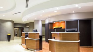 A reception area with two wooden reception desks, a dark wall with a recessed light, and a tiled floor.