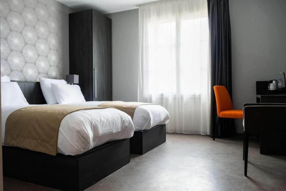 A modern hotel room with a double bed, a desk, and a chair.