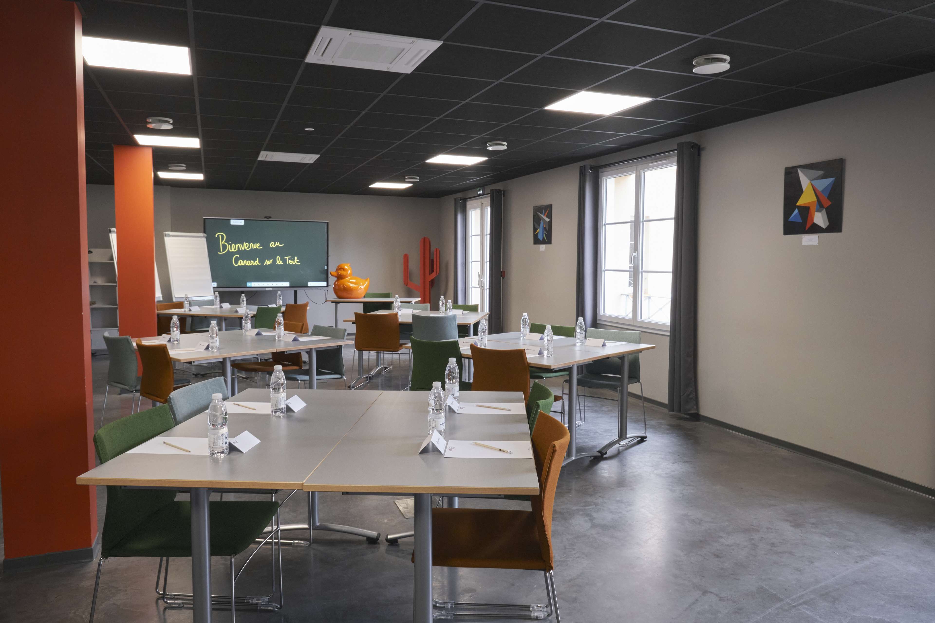 Une salle de conférence équipée de tables, de chaises et d’un tableau blanc.