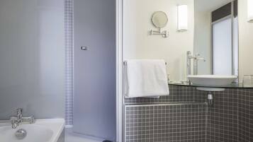 Un baño moderno con bañera, ducha, lavabo y espejo.