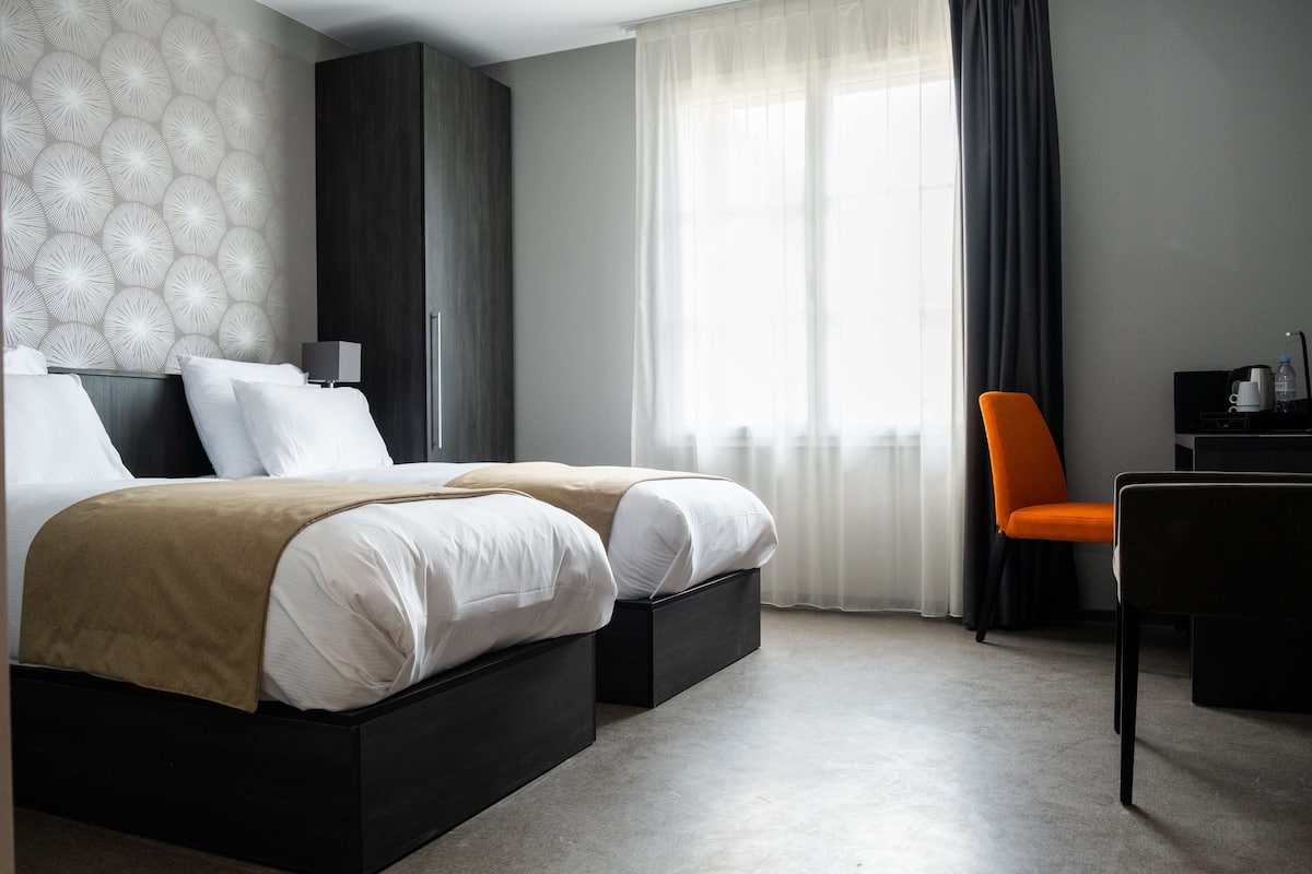 A modern hotel room with a double bed, a desk, and a chair.