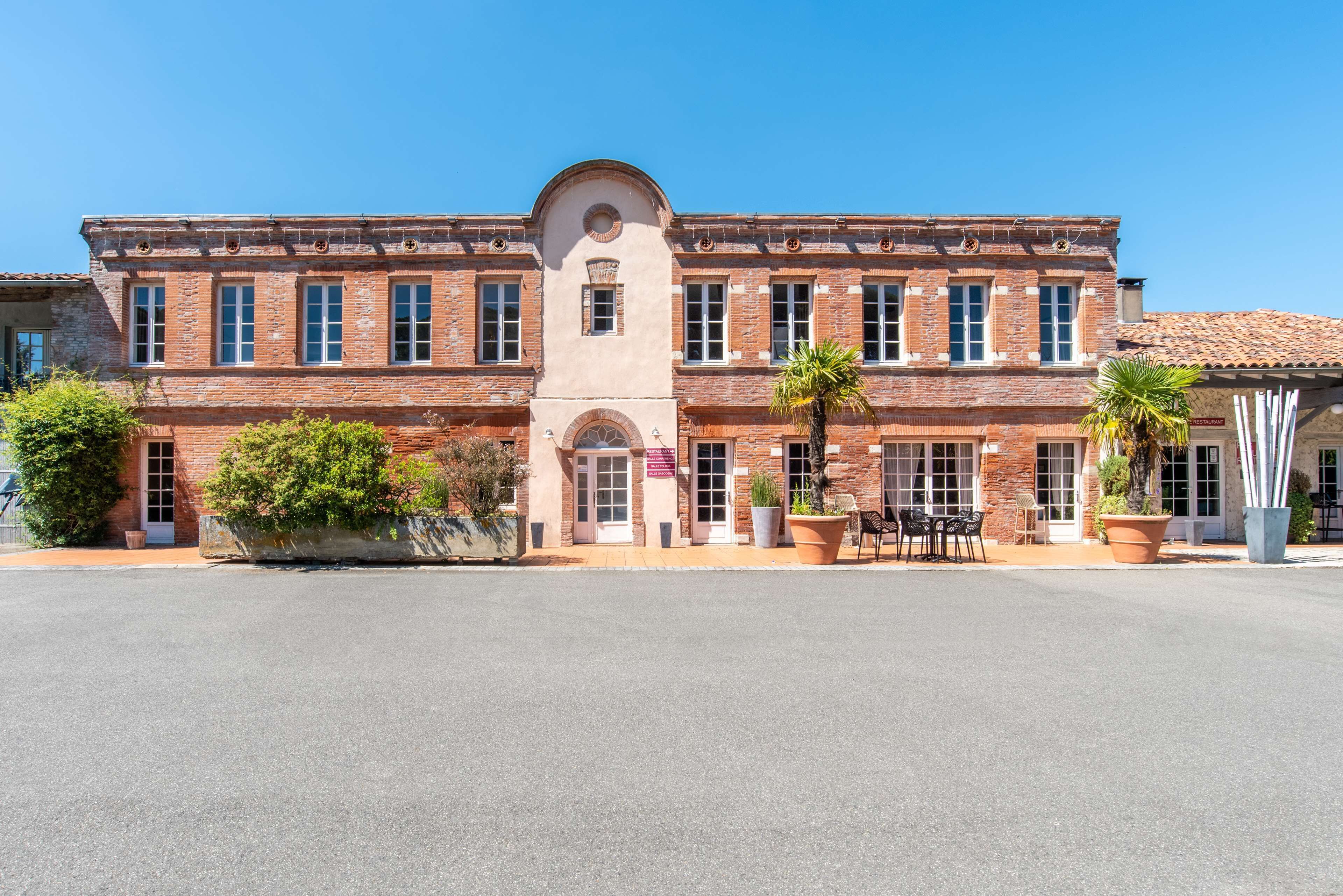 A historic building with a central arched entrance, large windows, and a brick facade.