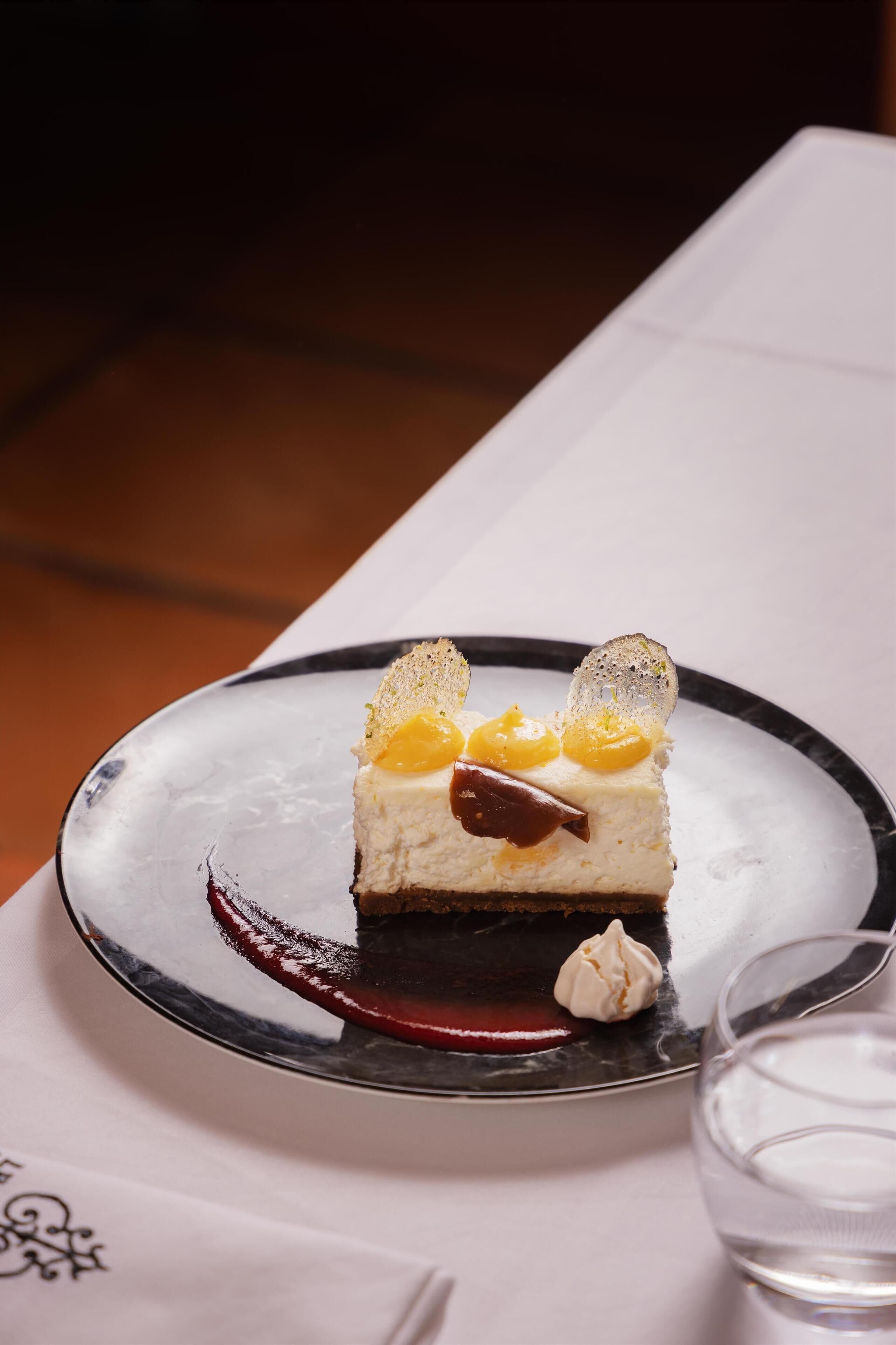 Un dessert présenté sur une assiette, avec un verre d’eau à proximité.
