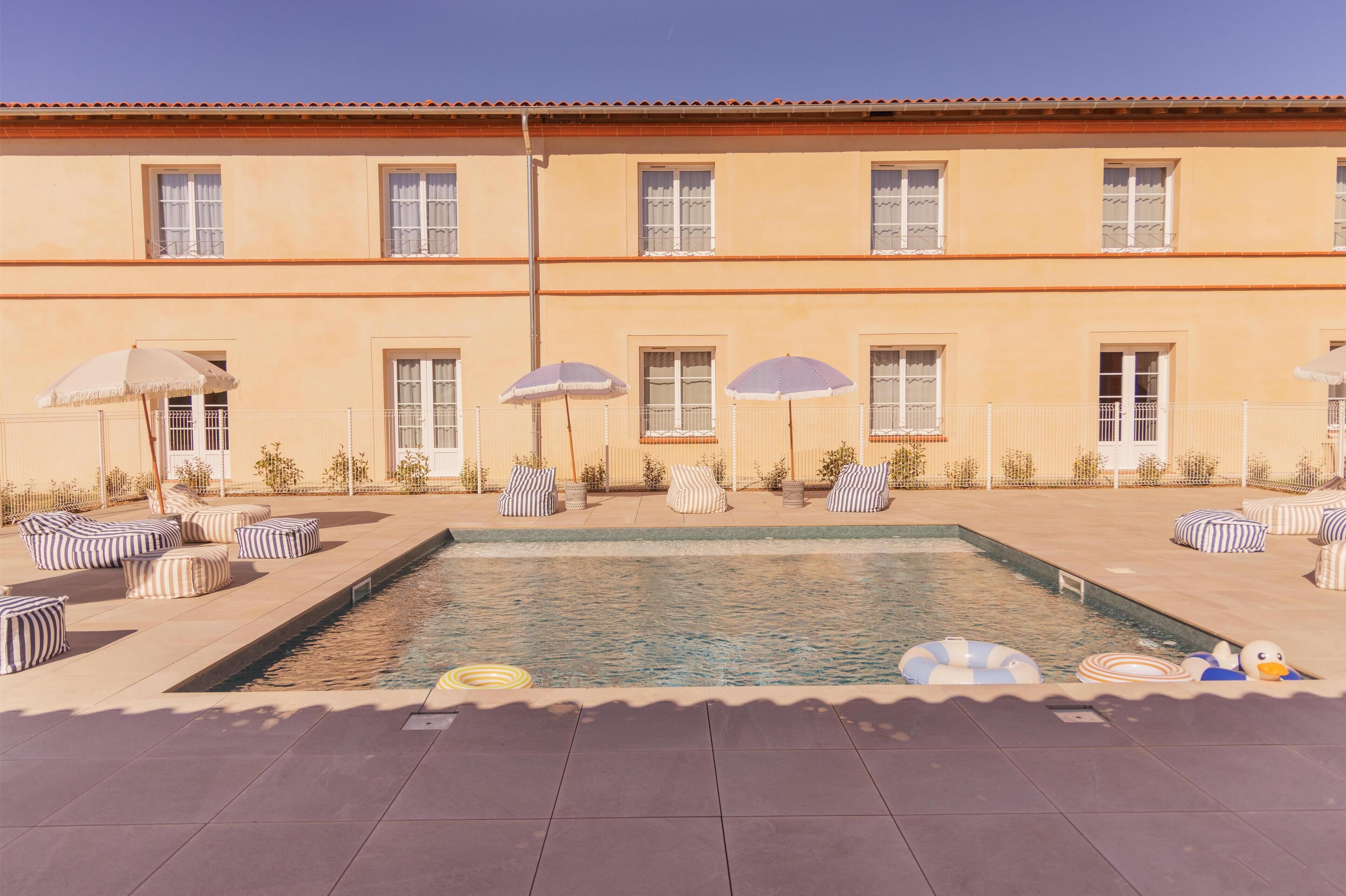 Una piscina al aire libre de temporada, sombrillas, tumbonas