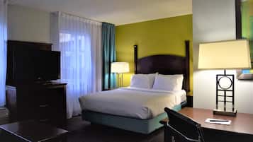 Ein Hotelzimmer mit einem Bett, einem Schreibtisch, einem Fernseher und einer Lampe.