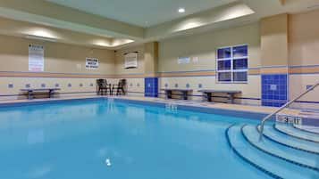 Ein Hallenbad mit klarem Wasser, Tiefenlinien und Sicherheitszeichen an den Wänden.