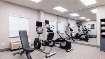 Et fitnessrum med motionscykler, romaskine og bænkpres.