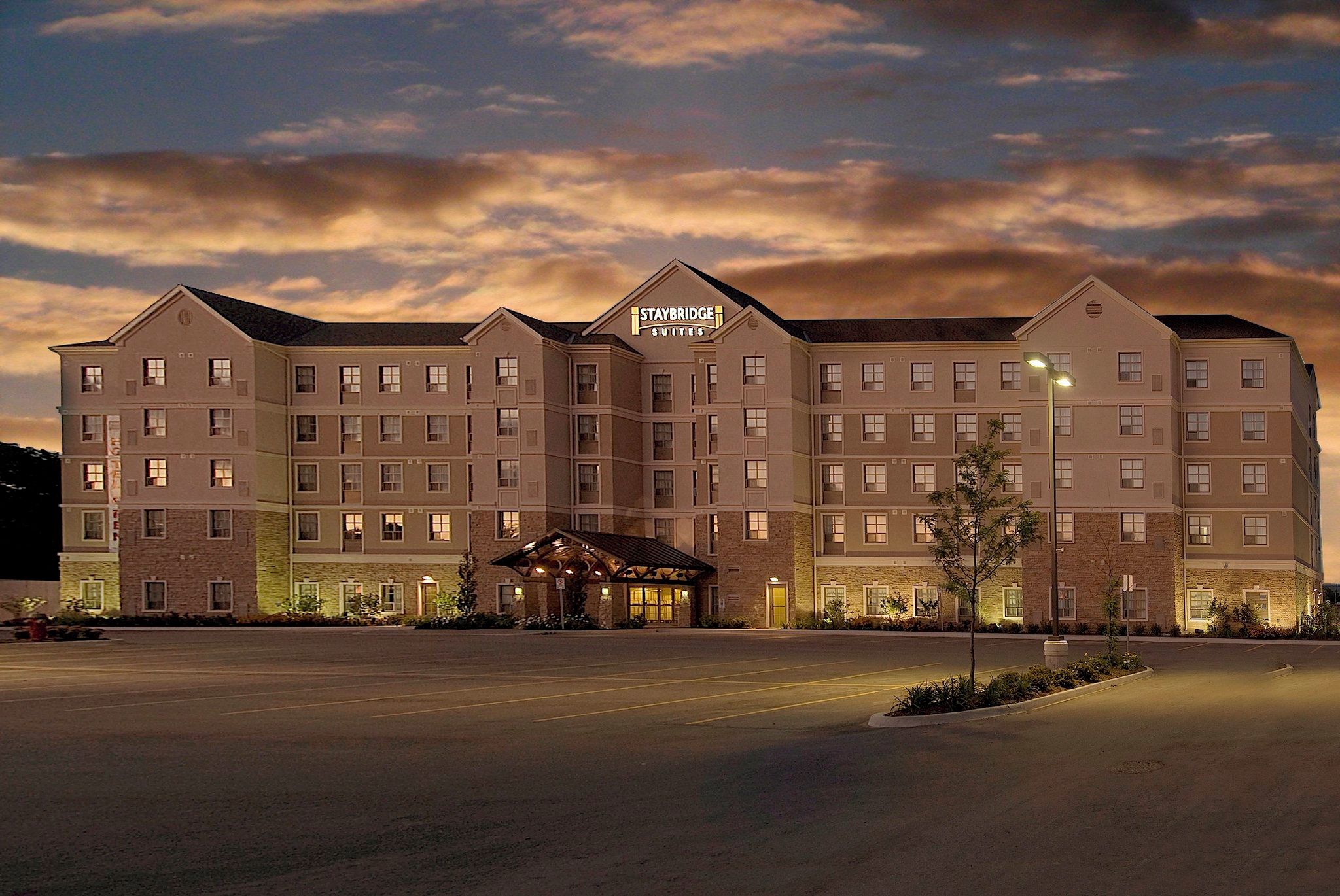 Un hôtel à plusieurs étages, doté d’une entrée principale et d’une enseigne indiquant « Staybridge Suites ».