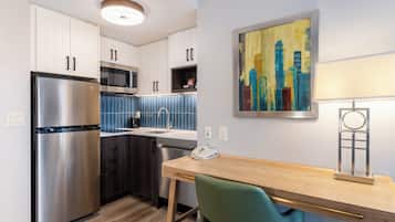 A modern kitchen with stainless steel appliances, a wooden dining table, and a cityscape painting on the wall.