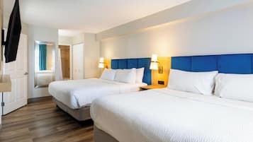 A hotel room with two beds, a TV, a bathroom, and a shower.