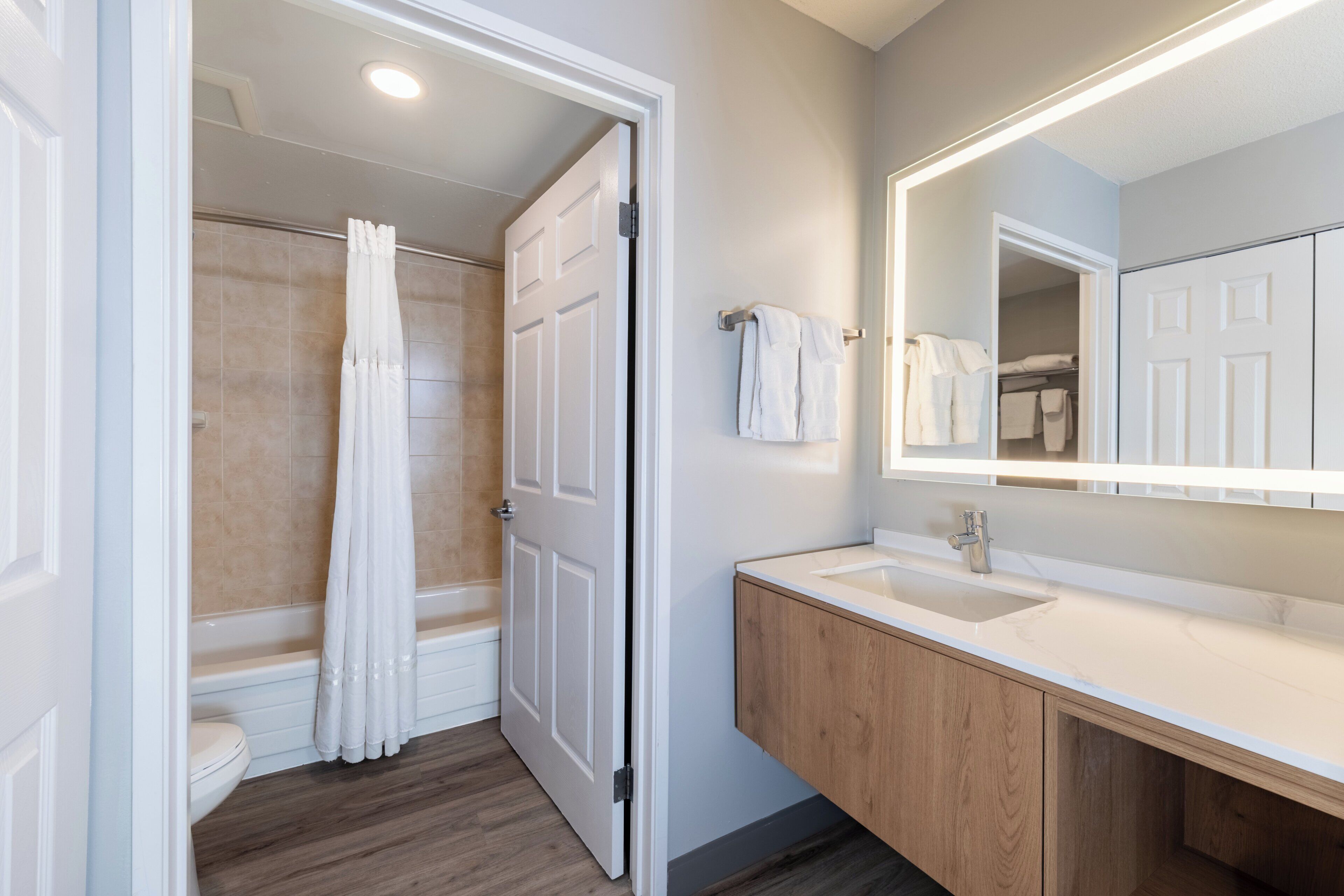 A bathroom with a shower, toilet, and vanity with a mirror.