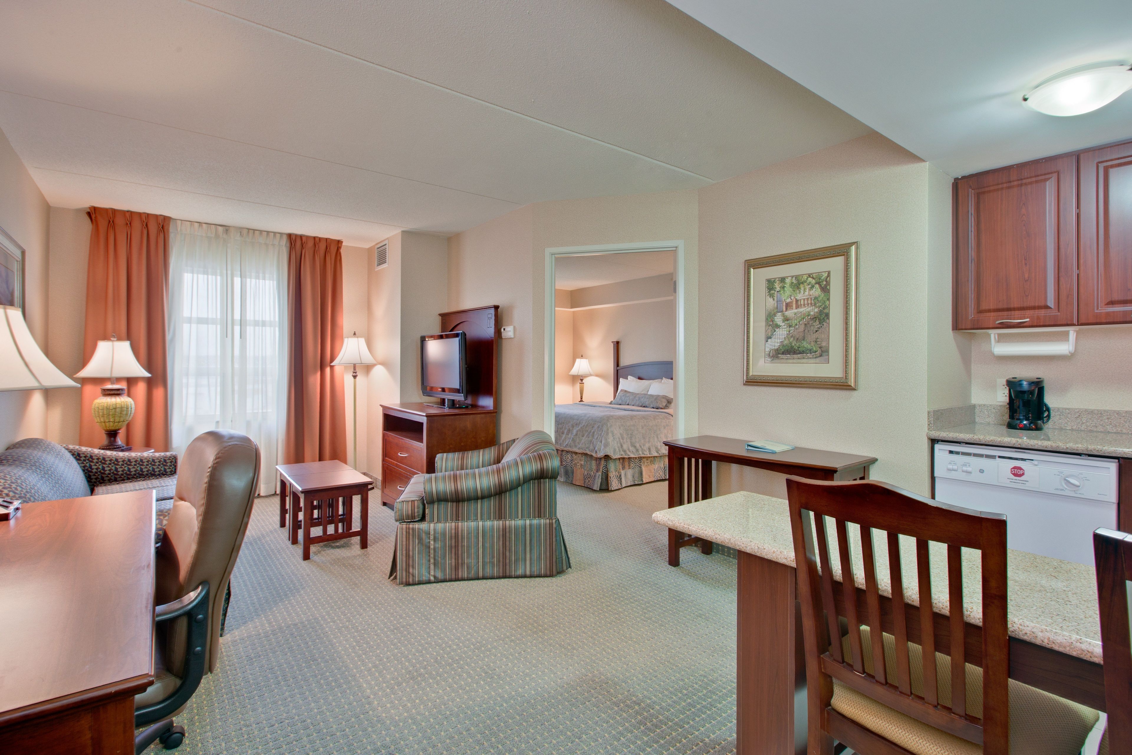Une chambre d’hôtel comprenant un coin repas, un lit, une télévision et un coin cuisine.