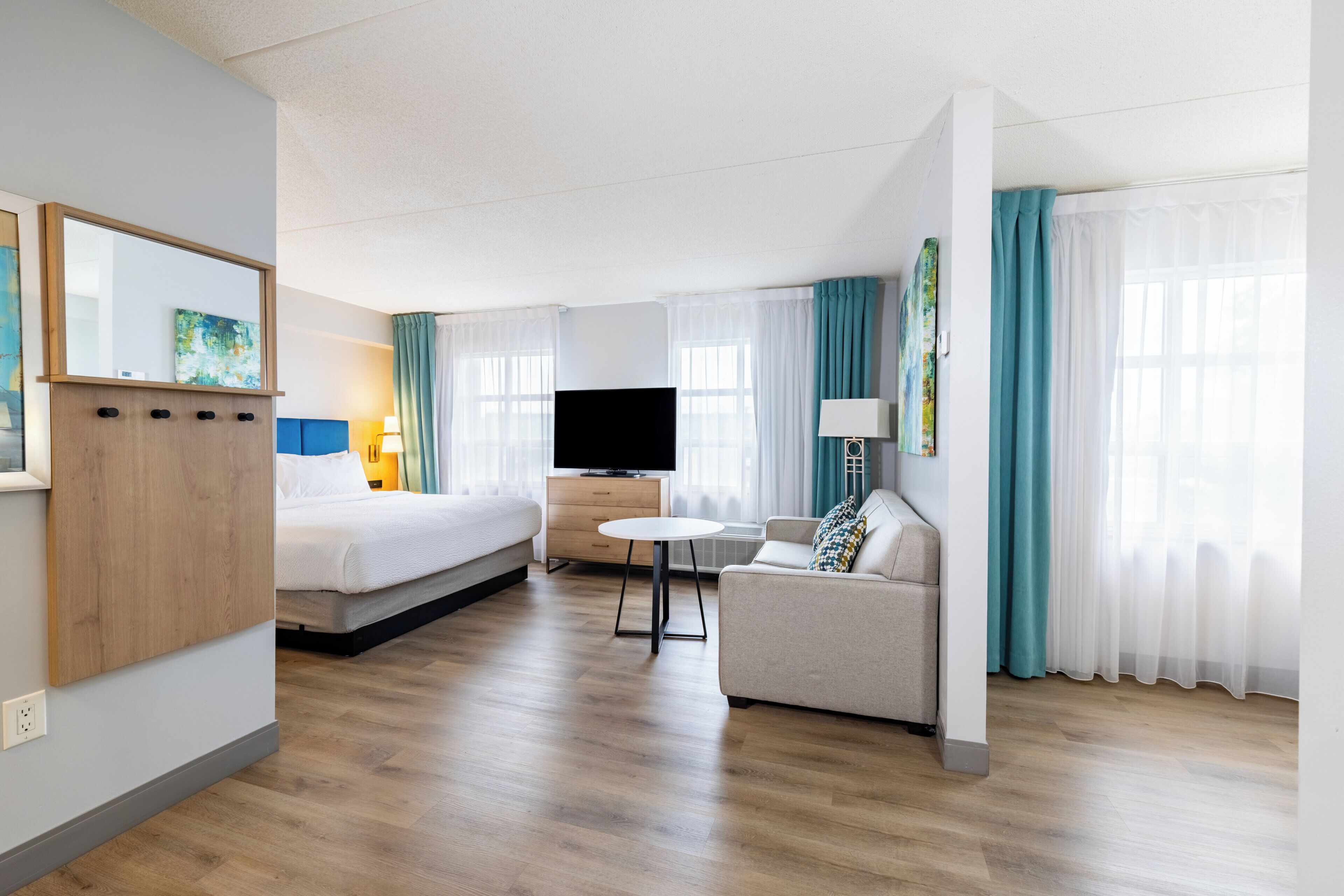 Een hotelkamer met een bed, een bank, een televisie, een tafeltje en een spiegel.