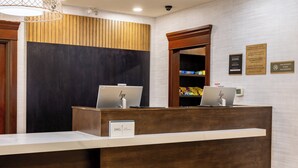 Una recepción con dos computadoras portátiles HP, un cartel de IHG One Rewards y un letrero de no fumar en la pared.