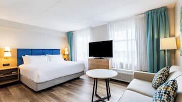 Una habitación de hotel con cama, sofá, televisión y una mesita.