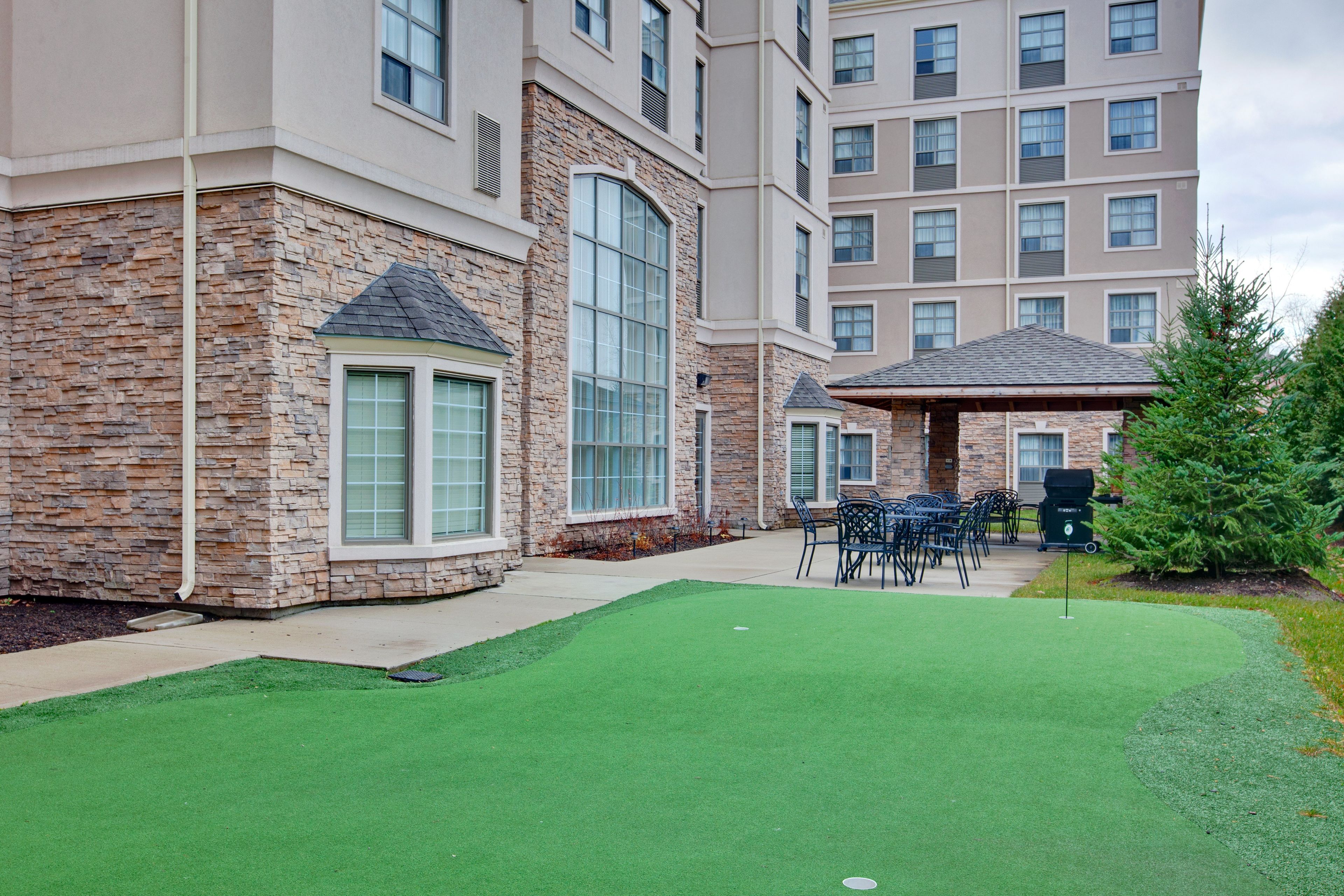 A building with a stone facade, large windows, and a patio area with artificial grass and outdoor furniture.