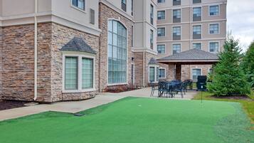 A building with a stone facade, large windows, and a patio area with artificial grass and outdoor furniture.