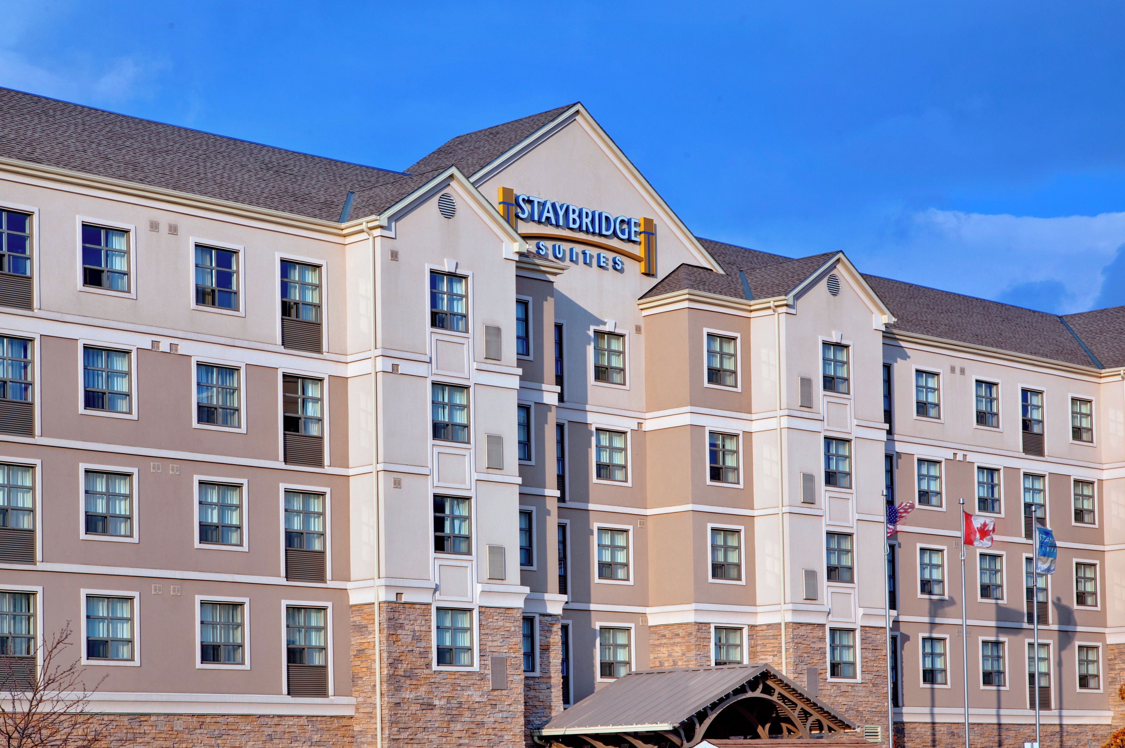 A Staybridge Suites hotel building with multiple floors, large windows, and a prominent sign.