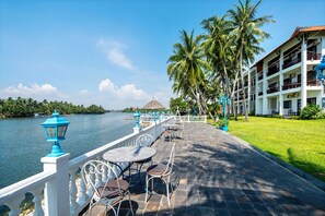 Un hotel frente al agua con terraza al aire libre, palmeras y vistas al mar.