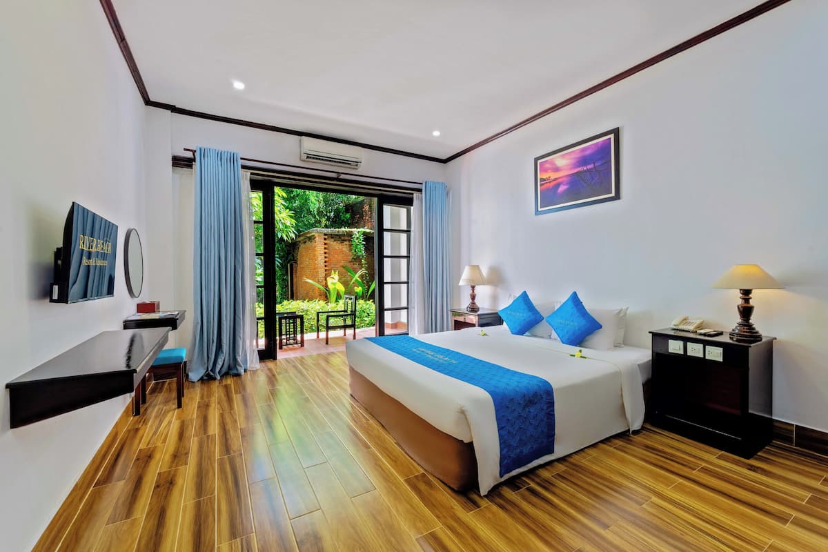 A hotel room with a bed, bedside tables, a desk, and a view of the outdoors.