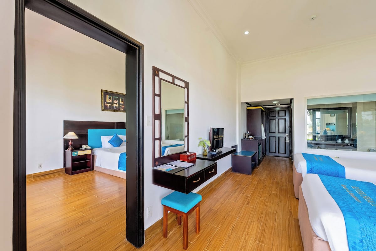 A hotel room with a bed, a desk, a chair, a mirror, a TV, and a bathroom door.