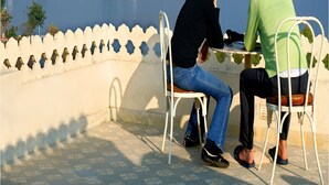 Two people seated at a table with a view of a lake and mountains in the background. - Rampratap Palace By Fateh Collection (Udaipur)