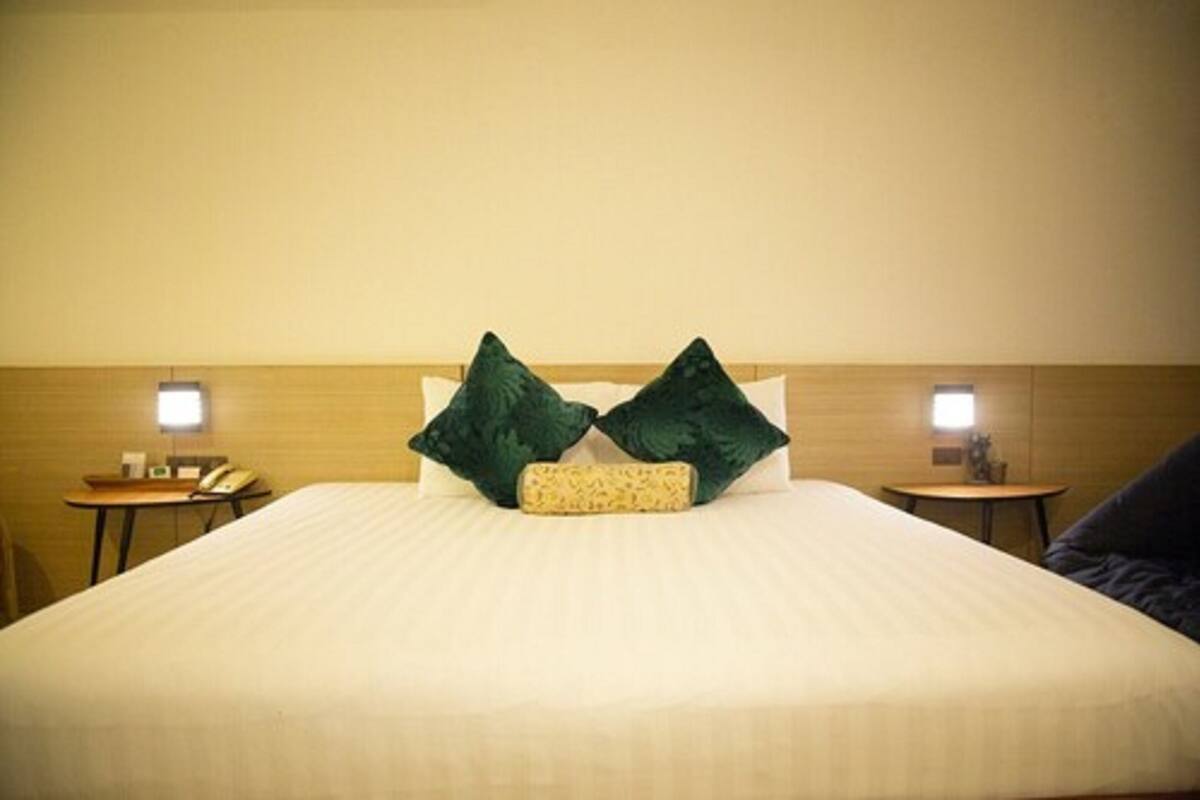 A hotel room with a large bed, two bedside tables, and a nightstand with a lamp.