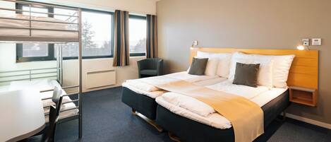A hotel room with a bunk bed, a desk, and a chair.