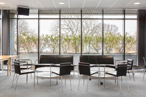Un espacio interior moderno con ventanas amplias, una mesa redonda y sillas negras.