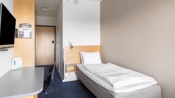 A hotel room with a bed, a desk, a chair, a television, and a door.