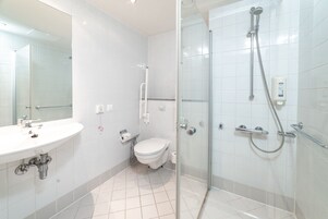 A modern bathroom with a glass-enclosed shower, a white sink, and a toilet.