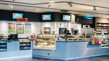 A food counter with a digital menu display, a refrigerated section, and a sign for 'Kasse'.