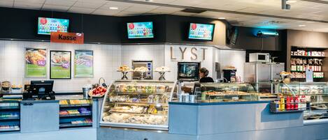 A food counter with a digital menu display, a refrigerated section, and a sign for 'Kasse'.