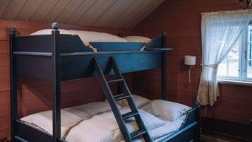 A bunk bed with a ladder, wooden walls, a window with curtains, and a wooden floor.