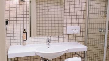 Un baño con dos lavamanos, un espejo grande y una cabina de ducha de cristal.