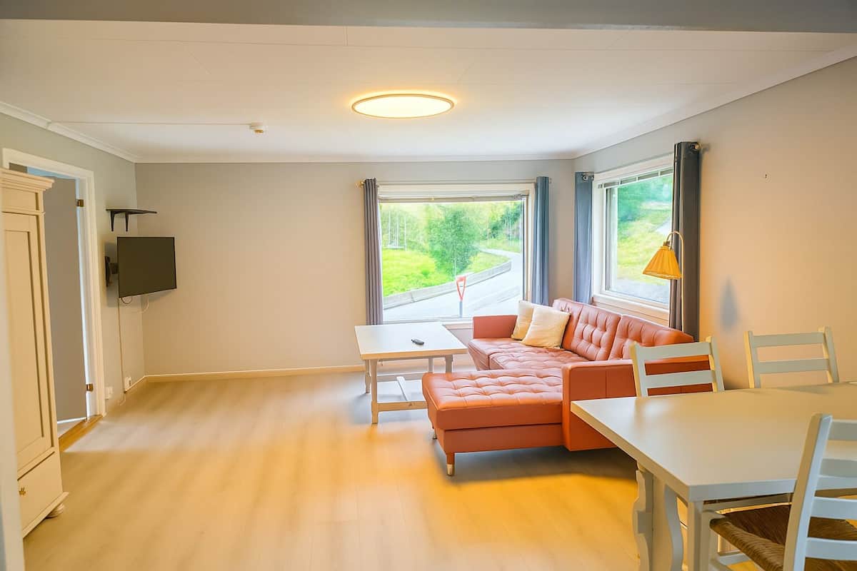 A modern room with a sofa, a table, and a TV mounted on the wall.