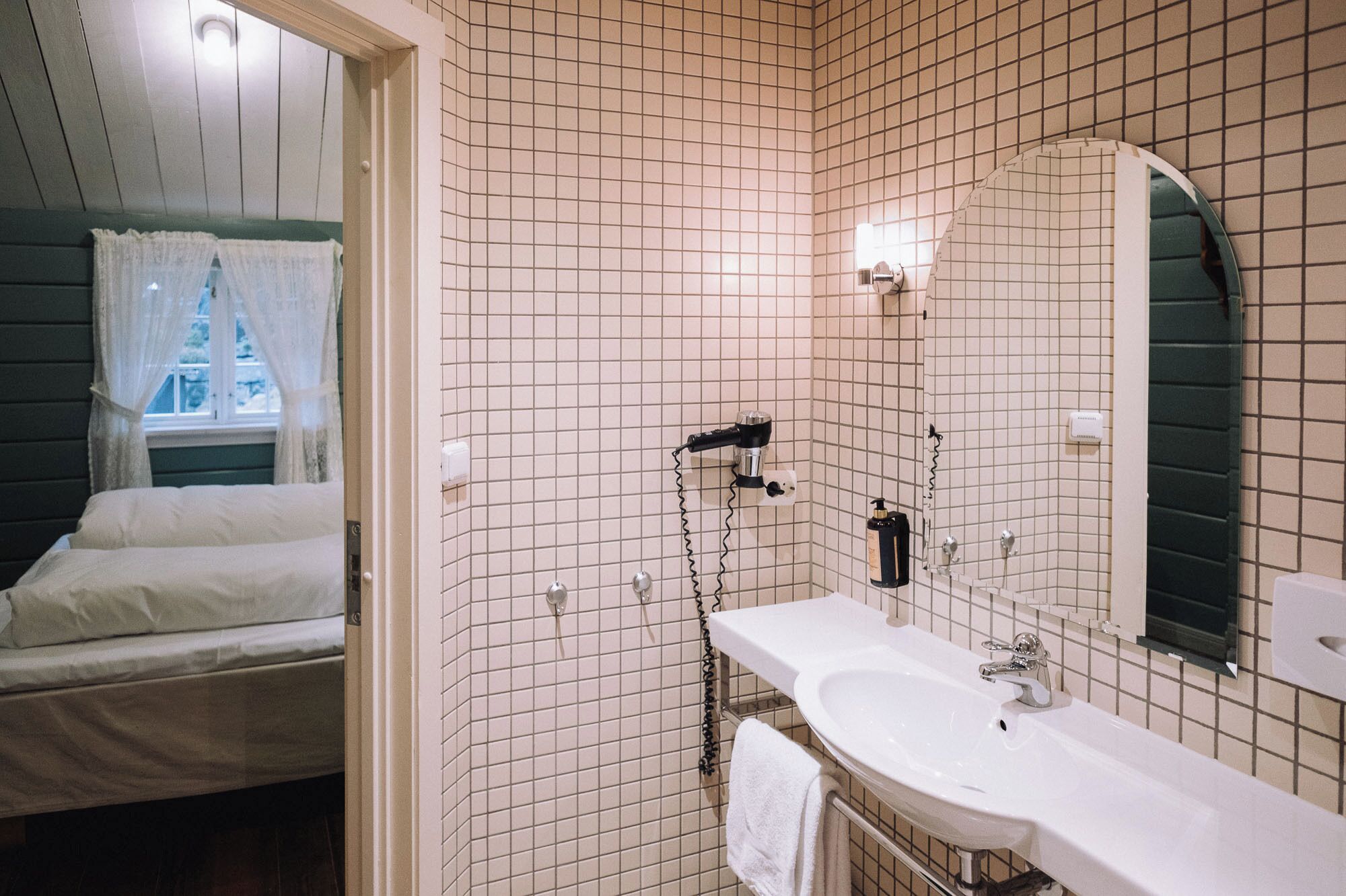 A bathroom with a white sink, a mirror, and a shower.