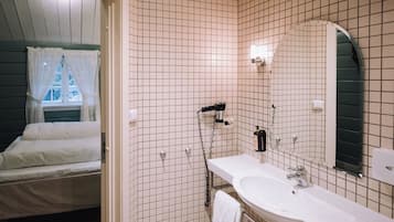 A bathroom with a white sink, a mirror, and a shower.