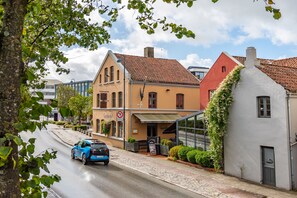 A street view with a blue car parked on the side, buildings with traditional architecture, and a clear sky. - GamlaVærket Gjæstgiveri og Tracteringssted (Sandnes)