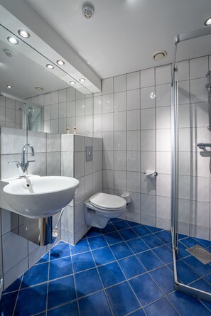 A modern bathroom with a white sink, toilet, and glass shower enclosure. - GamlaVærket Gjæstgiveri og Tracteringssted (Sandnes)