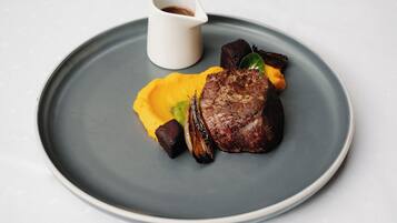 Une assiette contenant un steak, des légumes et une sauce.