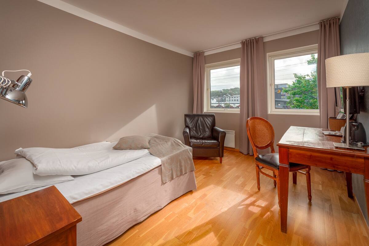 Quarto com cama, escrivaninha, cadeira e abajur.