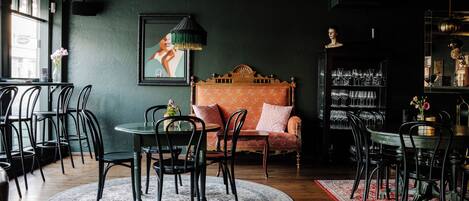 Una habitación acogedora con una mesa redonda, sillas, un sofá y una estantería llena de libros y objetos decorativos.