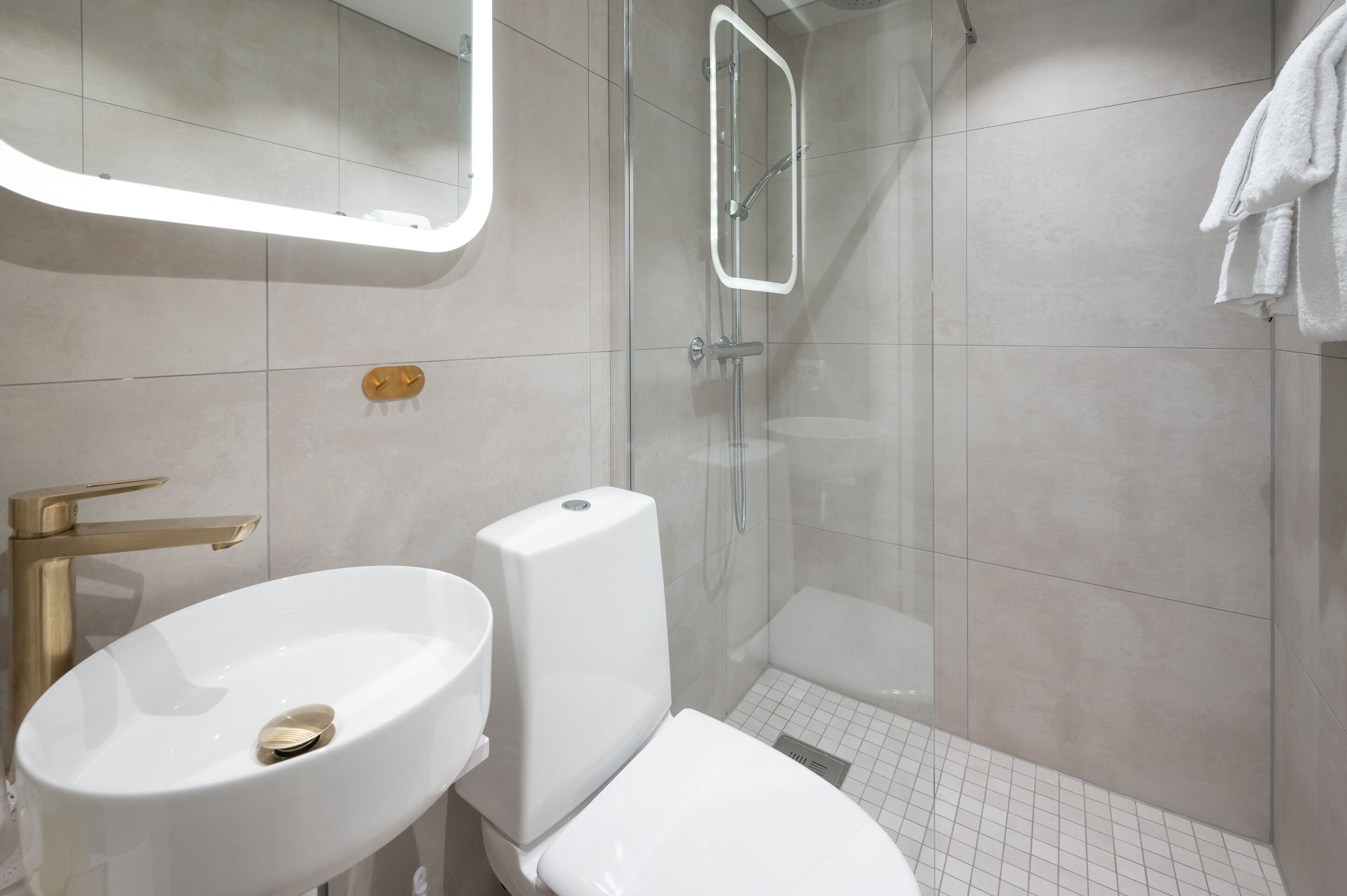 Un baño moderno con lavamanos, inodoro y ducha blancos.